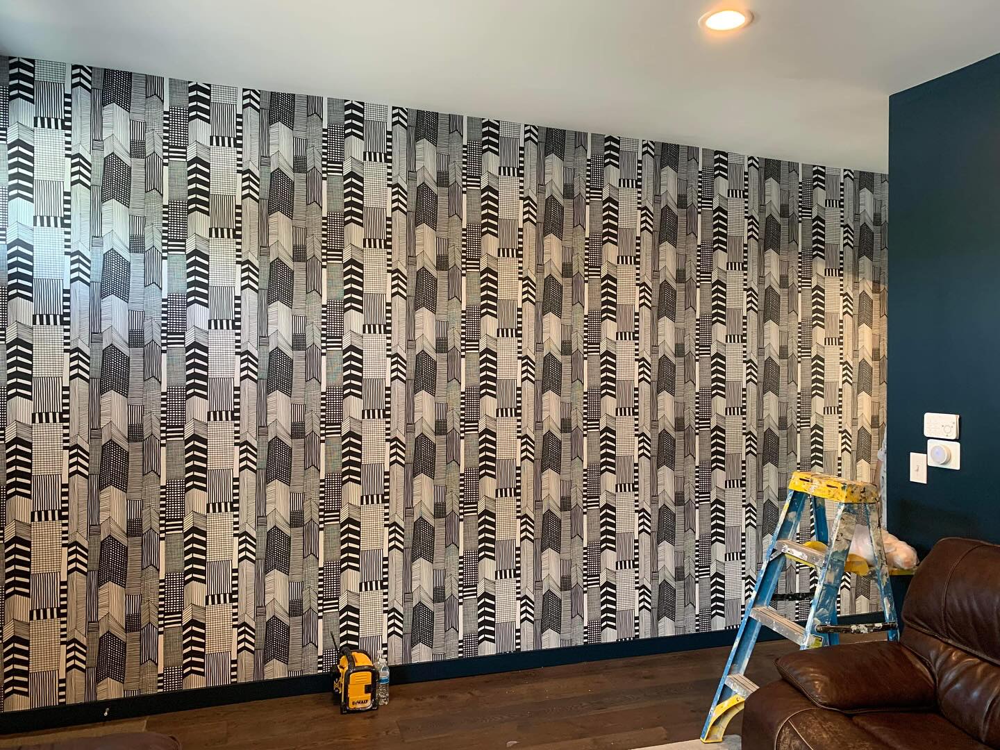 Professional wallpaper installer applying patterned wallcovering to a wall